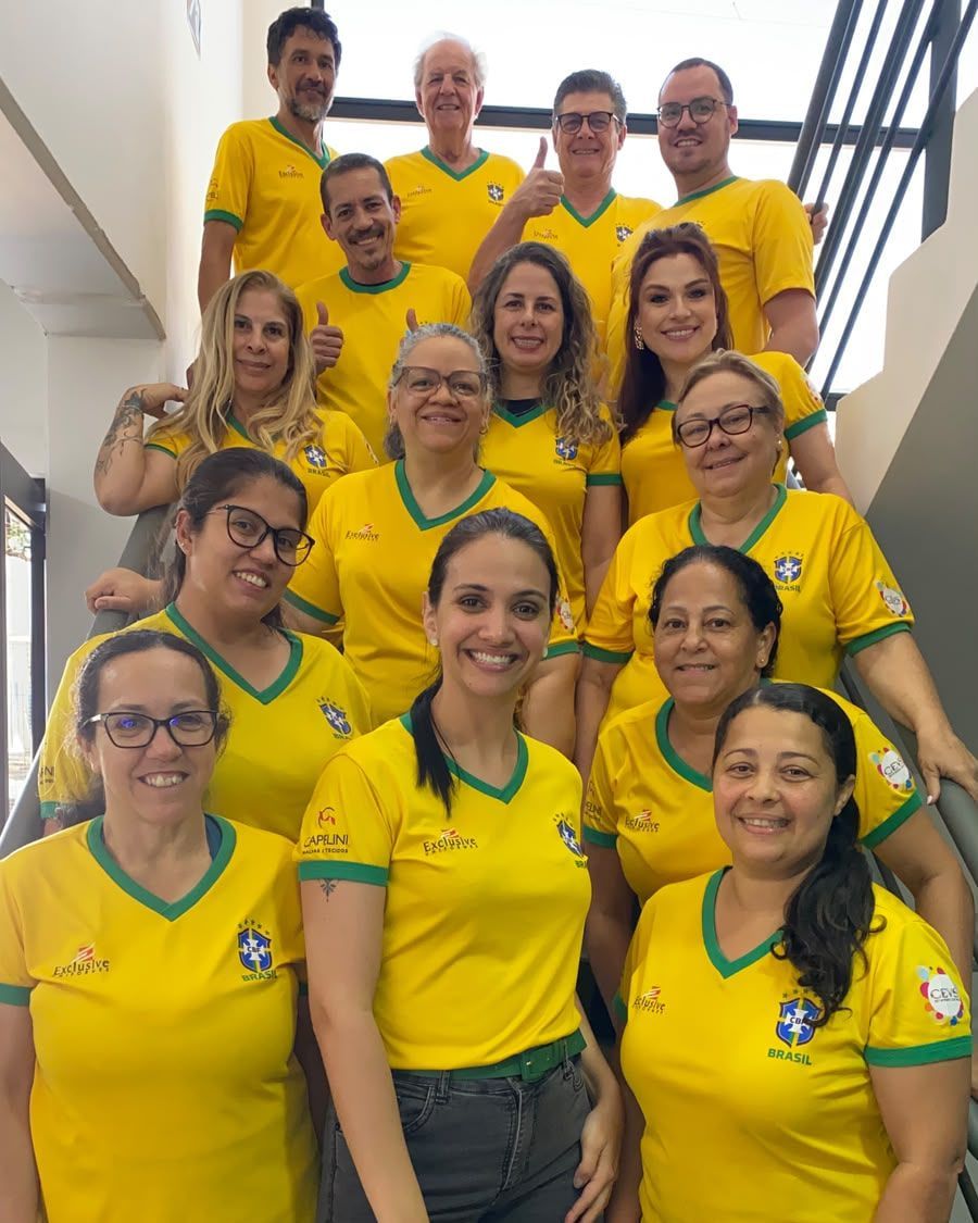 Equipe da Exclusive Uniformes reunida numa escada, vestindo camisas amarelas